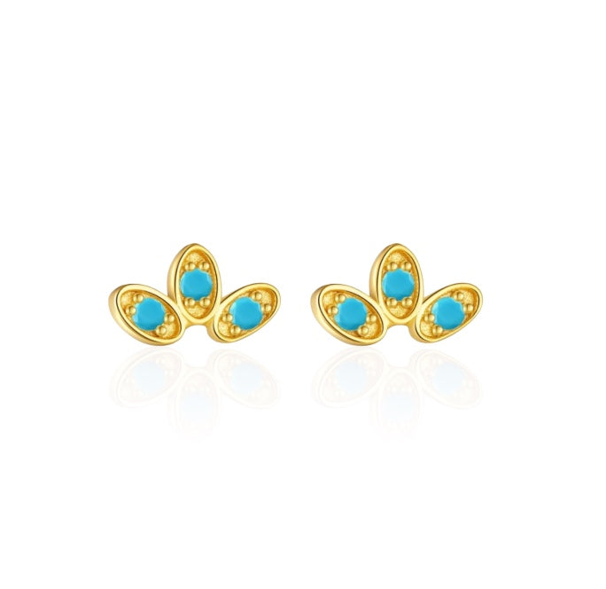 A set of elegant stud earrings with a curved fan design, featuring gold vermeil and colorful gemstone accents, displayed on a silky fabric.