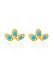 A set of elegant stud earrings with a curved fan design, featuring gold vermeil and colorful gemstone accents, displayed on a silky fabric.