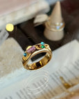 Gold ring with colorful gemstones on a textured surface