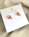 Gold and pink stud earrings on a JV Studios branded card.