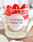 Strawberry cheesecake candle with red candle wick on a wooden surface